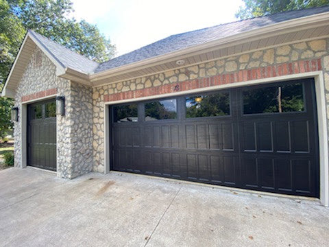 Newly installed black garage doors on a stone and brick house by Garage Doors & More in Bentonville, AR