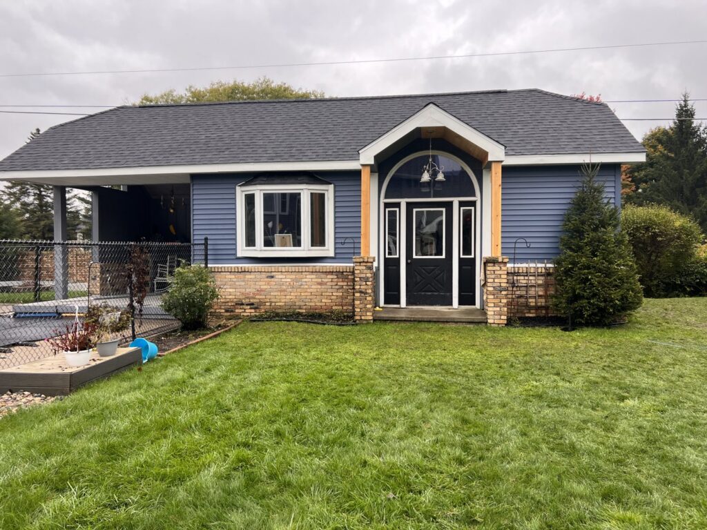 A residential home with newly installed blue siding and a dark roof by Murphy Builders- Genesee County in Ossineke, MI.