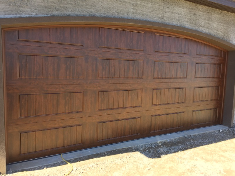A newly installed brown garage door with an arched top by Alpine Overhead Garage Door Service in Layton, UT.
