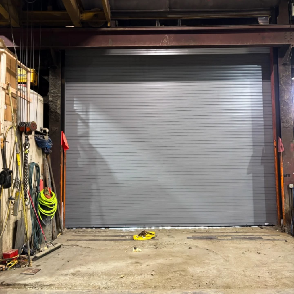 A newly installed commercial roll-up garage door inside a workshop by Alaska Door in Wasilla, AK.