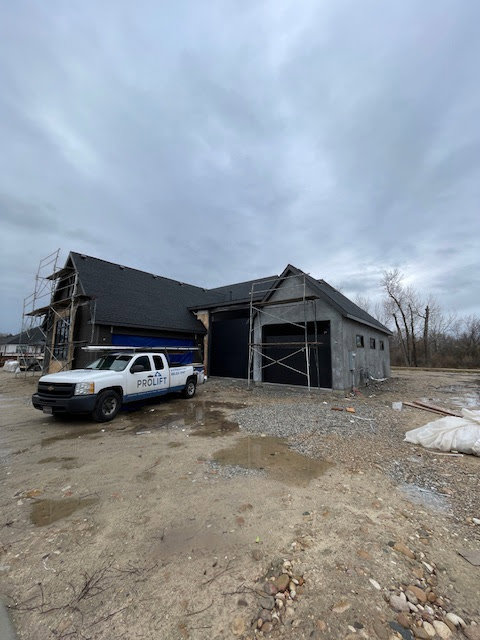 A ProLift Garage Doors of Canyon County truck at a new construction site with recently installed black garage doors in Nampa, ID.
