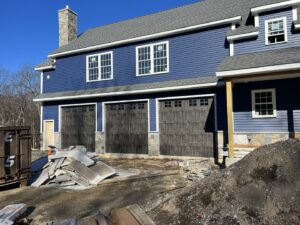 Three dark brown garage doors installed on a new construction blue house by RidgeLine Overhead Garage Door of CT in Danbury, CT