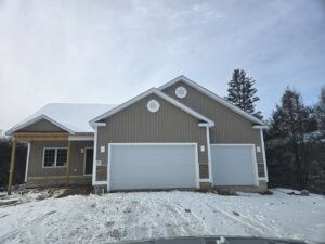 A new construction home with two newly installed white garage doors by Spring King Garage Doors in Middletown, CT