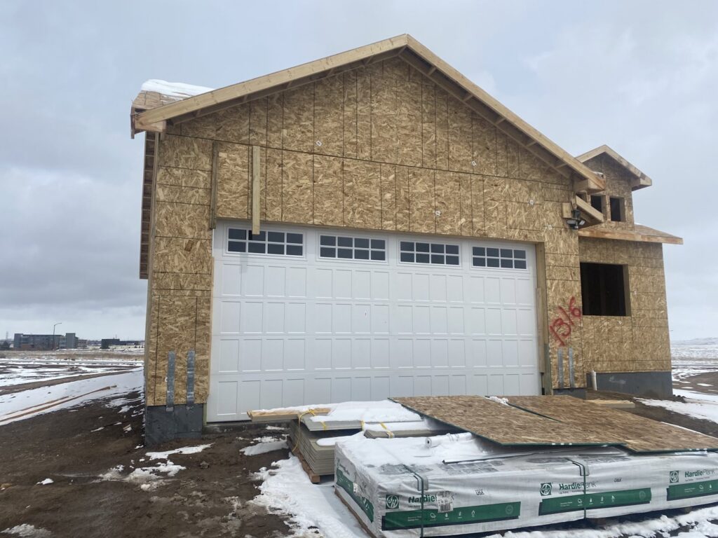 A large white garage door with windows installed on a house under construction by Apex Garage Doors in Columbus, OH.