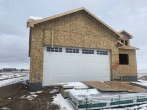 A large white garage door with windows installed on a house under construction by Apex Garage Doors in Columbus, OH.