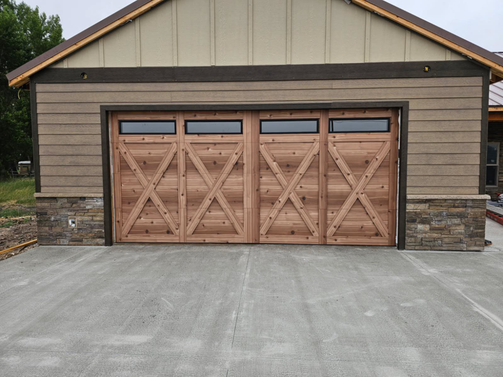 A newly installed custom wood garage door with windows on a residential building by Devildog Dock N Door in Helena, MT.