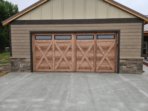 A newly installed custom wood garage door with windows on a residential building by Devildog Dock N Door in Helena, MT.