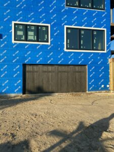 A new dark brown garage door installed on a house under construction by Hickman Overhead Door in Milford, DE.