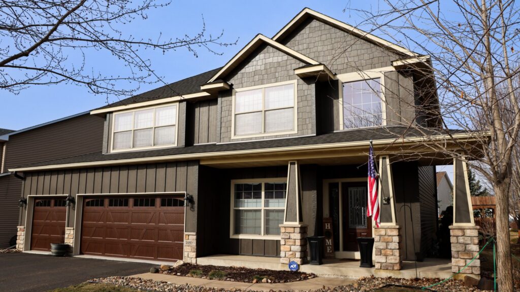A newly sided house featuring dark brown siding and decorative stone accents, completed by Archcraft Exteriors in South Saint Paul, MN.