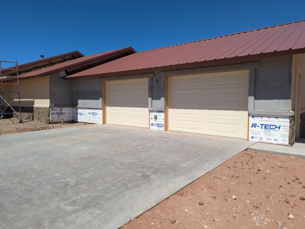 Two new light-colored panel garage doors installed on a house under construction by Precision Garage Door of Albuquerque and Santa Fe, NM.