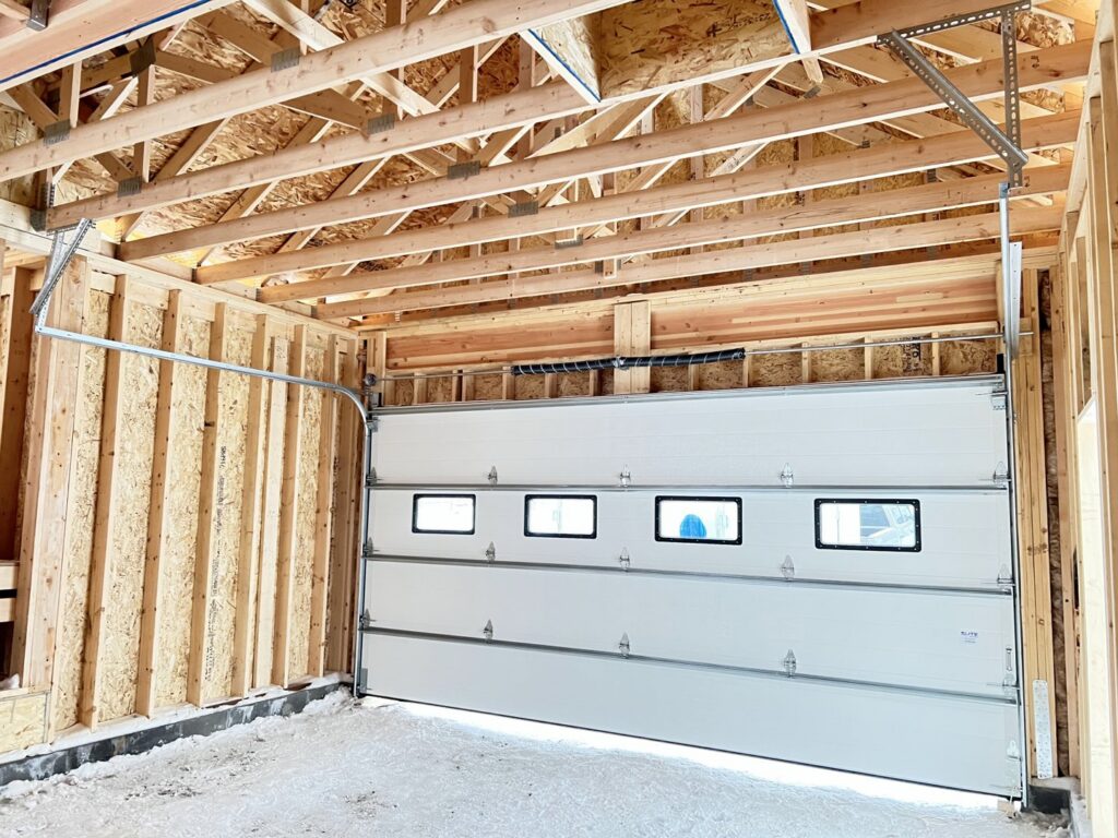 Interior view of a newly installed white garage door and track system in a residential garage by Elite Doors in Wasilla, AK.