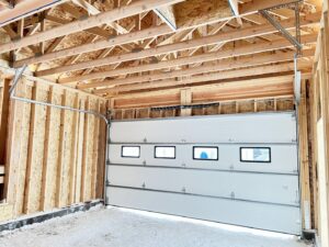 Interior view of a newly installed white garage door and track system in a residential garage by Elite Doors in Wasilla, AK.