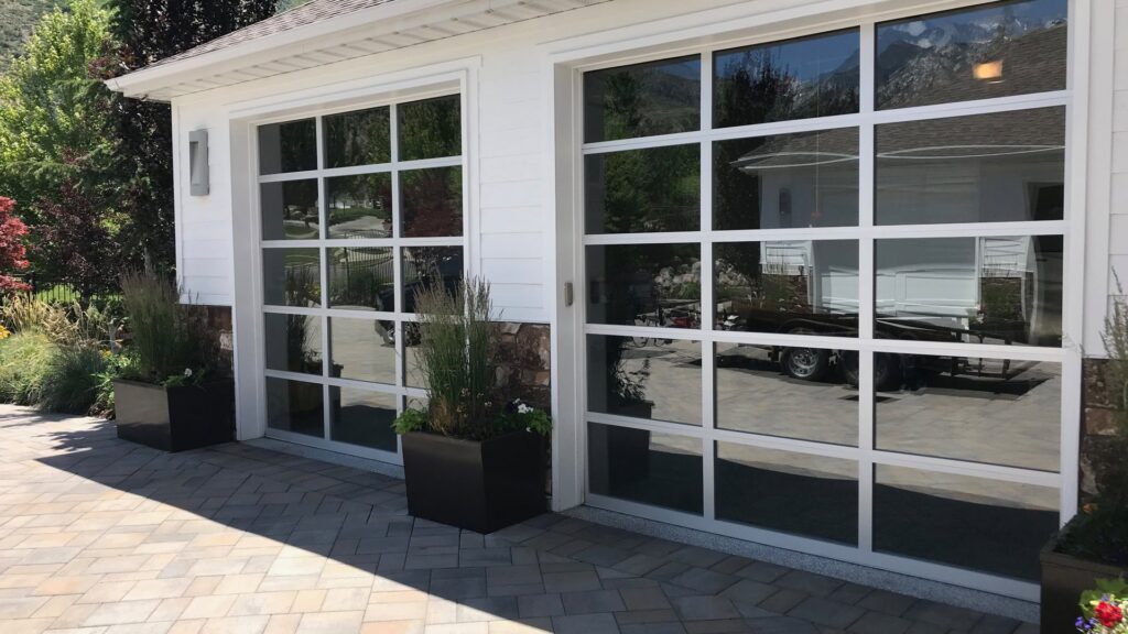 New glass garage doors installed on a residential property by Up N Over Garage Doors LLC in Layton, UT.