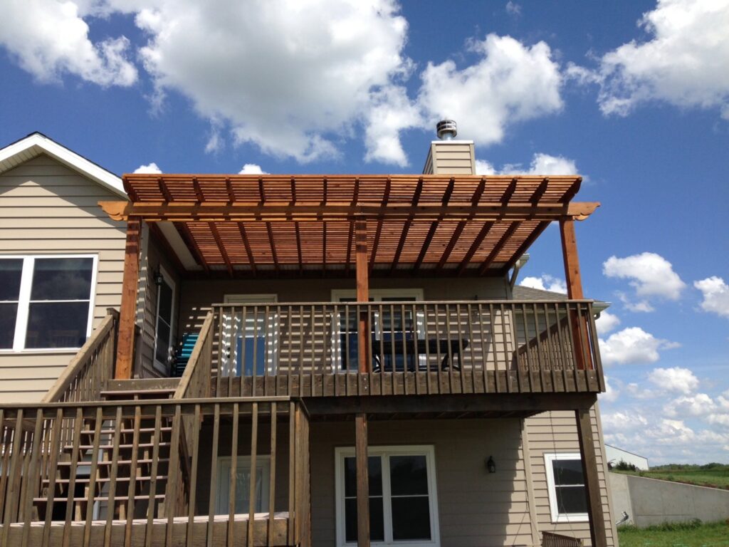 A house with newly installed light green siding and a wooden porch structure under construction by Arrow Exteriors Inc. in Topeka, KS