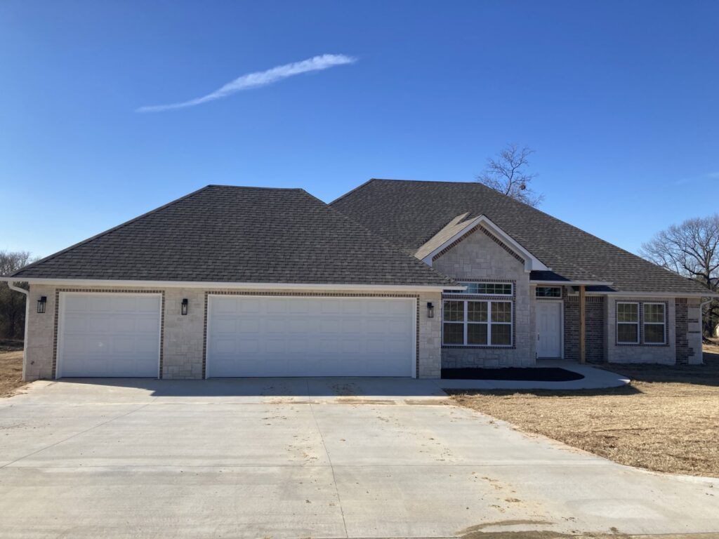 A newly constructed home featuring three white garage doors installed by GRIT Garage Doors in Alma, AR