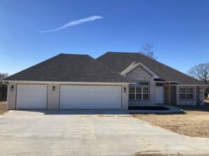 A newly constructed home featuring three white garage doors installed by GRIT Garage Doors in Alma, AR