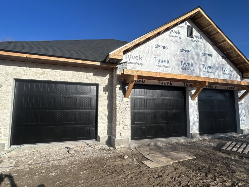 A newly constructed house featuring two black garage doors installed by Barrett Overhead Doors in Idaho Falls, ID.