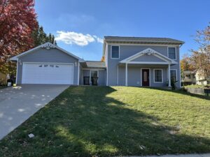 A residential home featuring new light blue siding and a white garage door, installed by DJ Paz All Siding & Roofing Construction in Iowa City, IA