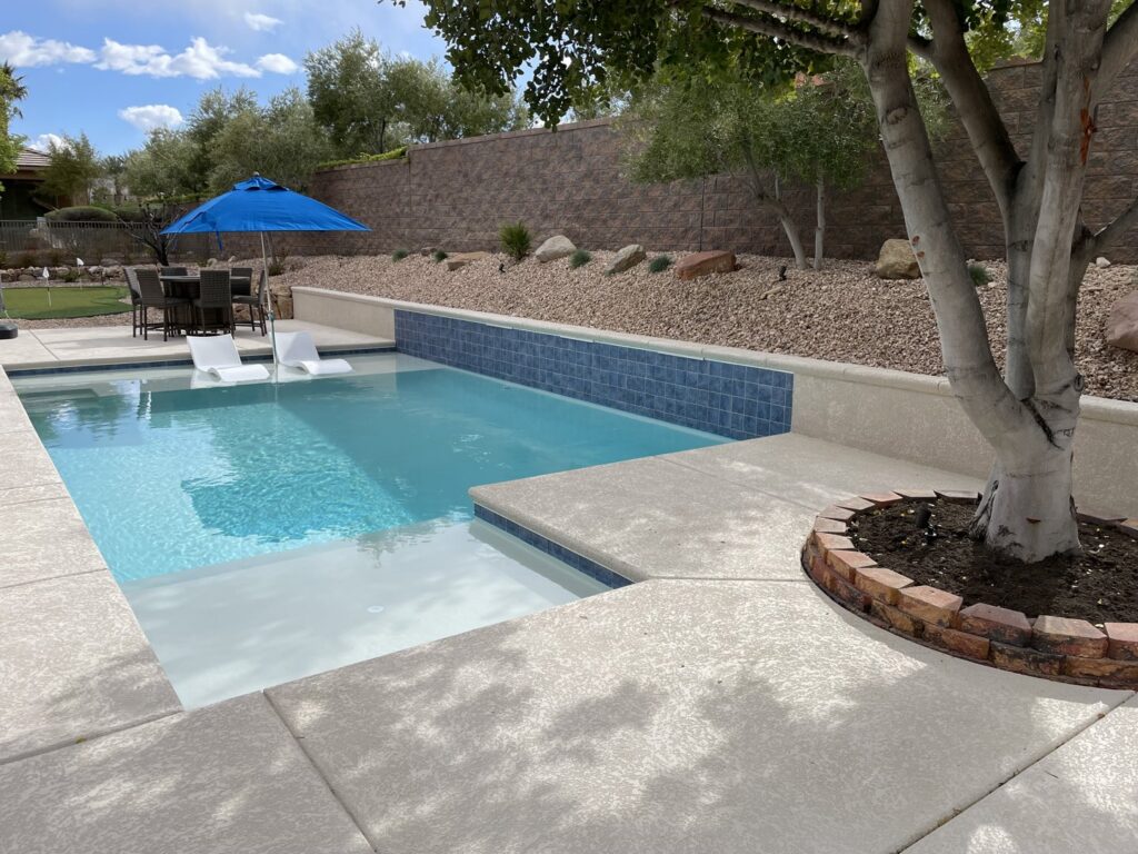 A newly constructed pool featuring a sun shelf and blue tile wall by Steve Breck Pools in Las Vegas, NV.