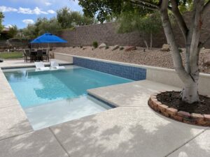 A newly constructed pool featuring a sun shelf and blue tile wall by Steve Breck Pools in Las Vegas, NV.