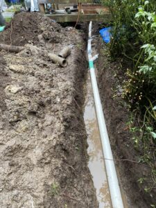 A new PVC pipe installed in a muddy trench, showing a drain or sewer line repair by DNA Drain Cleaning & Sewer in Tulalip, WA.