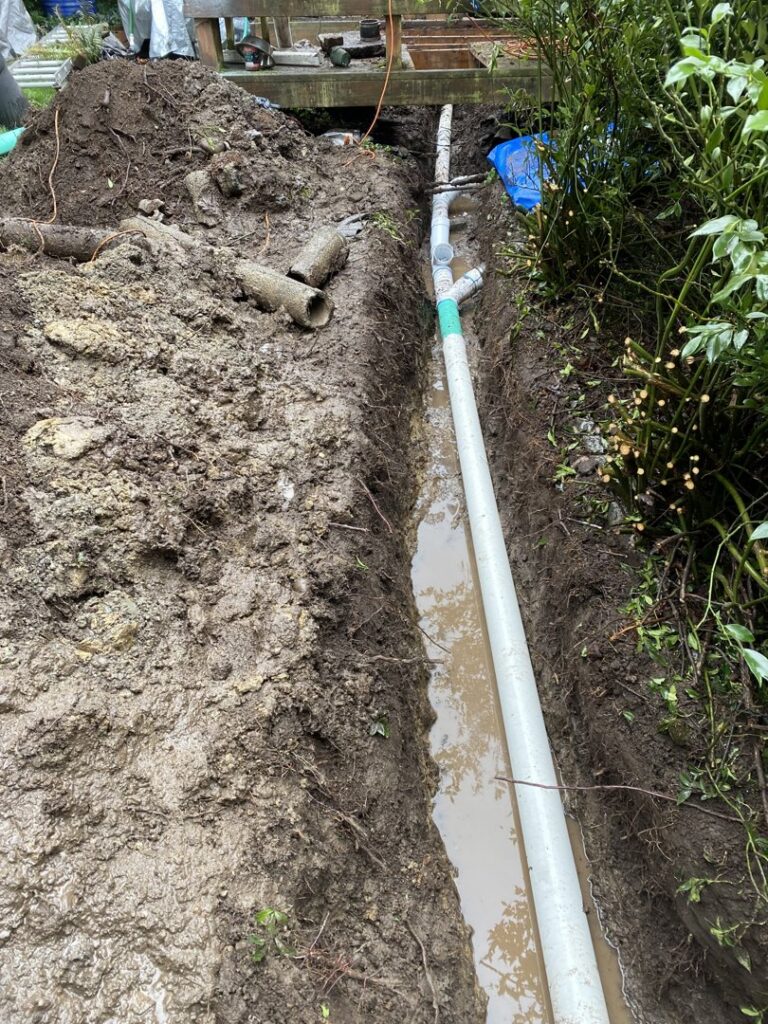 A new PVC pipe installed in a muddy trench, showing a drain or sewer line repair by DNA Drain Cleaning & Sewer in Tulalip, WA.