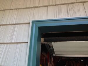 Close-up of new white siding and blue trim around a garage door by Capital Siding, Windows & Roofing, Woodbury, MN.