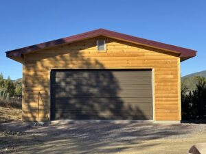 A newly installed single garage door on a wooden outbuilding by Overhead Door Company of Albuquerque in Albuquerque, NM.