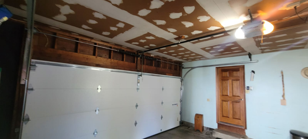 A newly installed white garage door with tracks and opener inside a garage by A1 Garage Guy Wes in Picture Rocks, AZ.