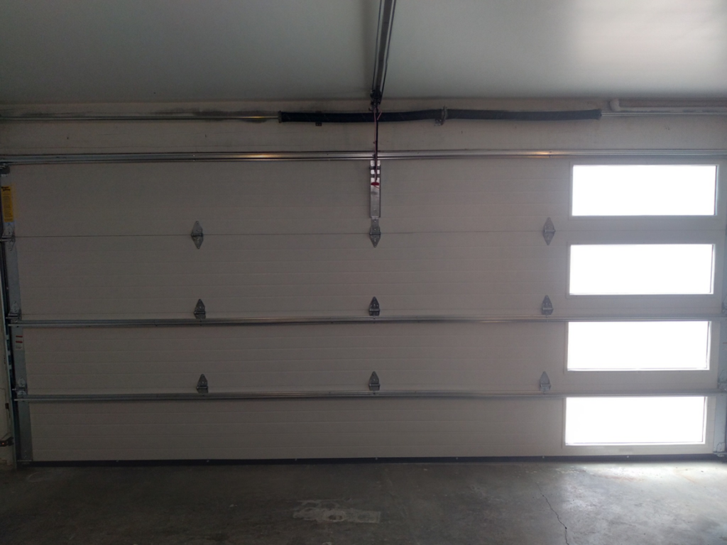 A newly installed white sectional garage door with horizontal windows by Cactus Garage Doors, Inc. in North Las Vegas, NV.