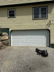 A newly installed white garage door on a yellow house by Mascolo Overhead Doors & Maintenance in Brookfield, CT.