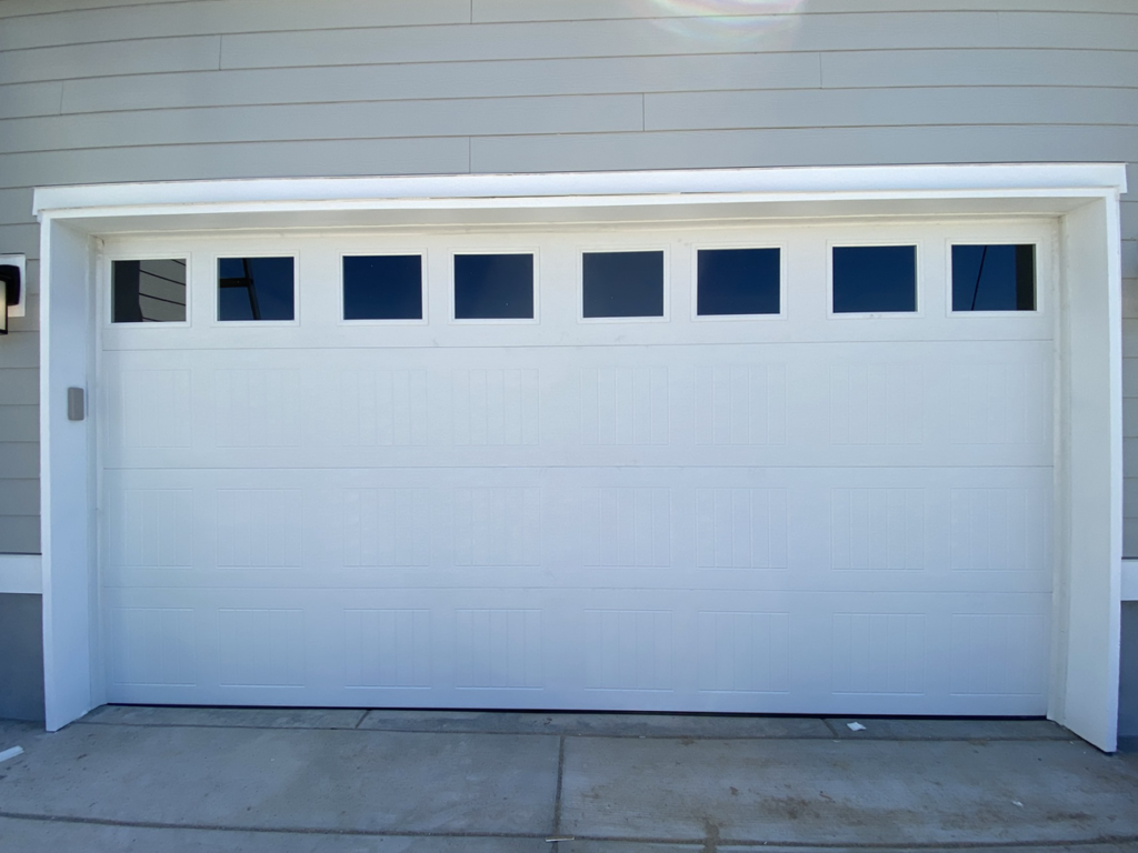 A newly installed white garage door with top windows by Next Level Garage Doors in Locust Grove, GA.