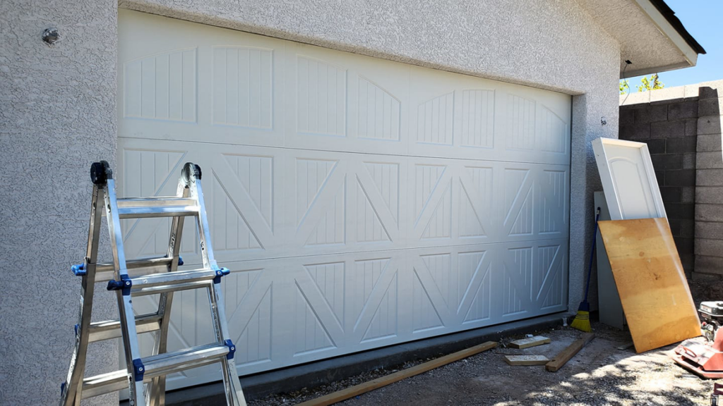 A newly installed white garage door with a ladder and tools nearby, indicating a recent job by Pioneer Overhead Door in Las Vegas, NV