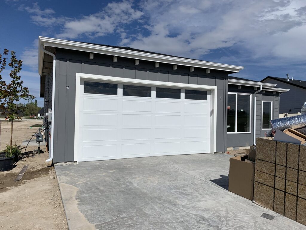 A newly installed white garage door on a modern gray house by Sawtooth Garage Doors in Boise, ID.