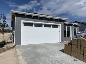 A newly installed white garage door on a modern gray house by Sawtooth Garage Doors in Boise, ID.