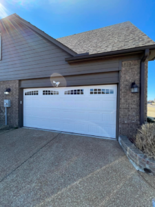 A newly installed white garage door with windows on a modern home by Ultimate Garage Doors LLC in Olive Branch, MS.