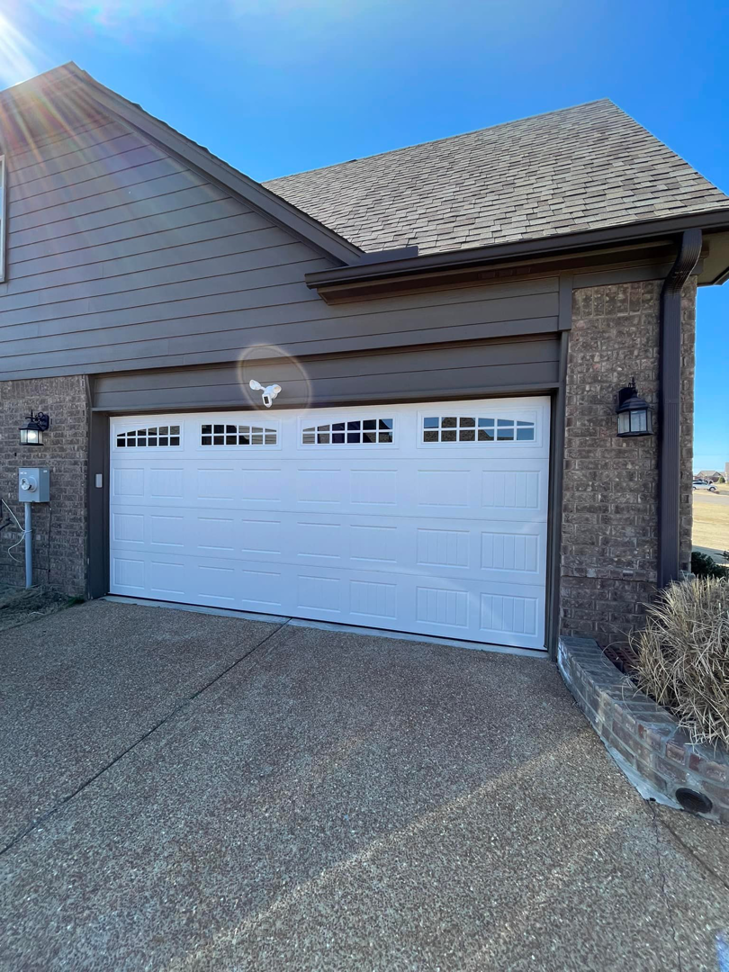 A newly installed white garage door with windows on a modern home by Ultimate Garage Doors LLC in Olive Branch, MS.