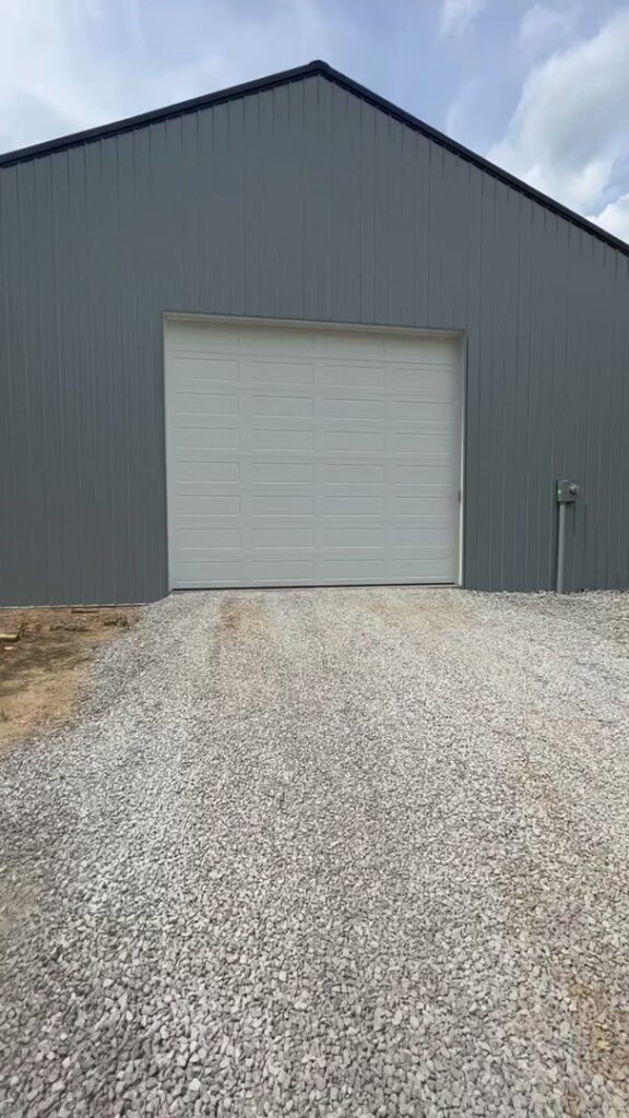 A newly installed white panel garage door on a modern grey metal building by 4thgenerationsdoors in Huntington, WV.