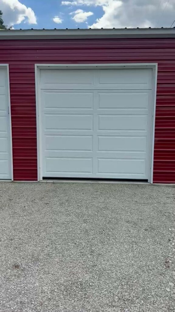 A newly installed white panel garage door on a vibrant red metal building by 4thgenerationsdoors in Huntington, WV.
