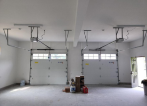 Interior view of a garage with newly installed white garage doors and openers by Compton Doors, Inc. in Attleboro, MA
