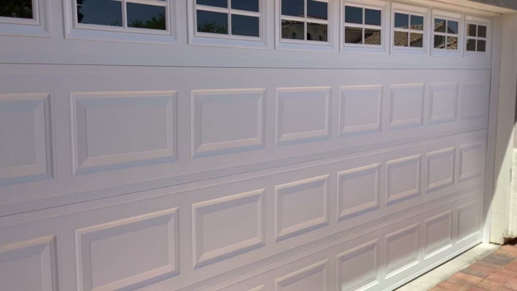 A newly installed white panel garage door with decorative windows, showcasing quality work by American Veteran Garage Door Repair Henderson, NV.