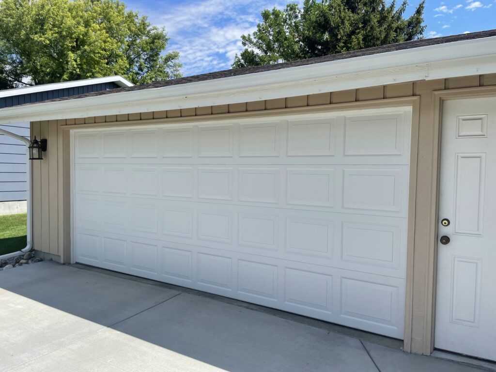 A new white panel garage door installed on a residential home by Elite Garage Door Service & Repair in Billings, MT.