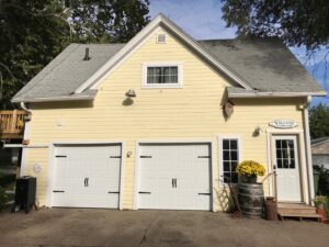 A residential home with two new white panel garage doors installed by JLM Garage Doors Omaha in Papillion, NE.