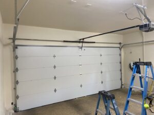 A newly installed white paneled garage door with tools and a ladder nearby by Legacy ODS Garage Door Services in Las Vegas, NV.