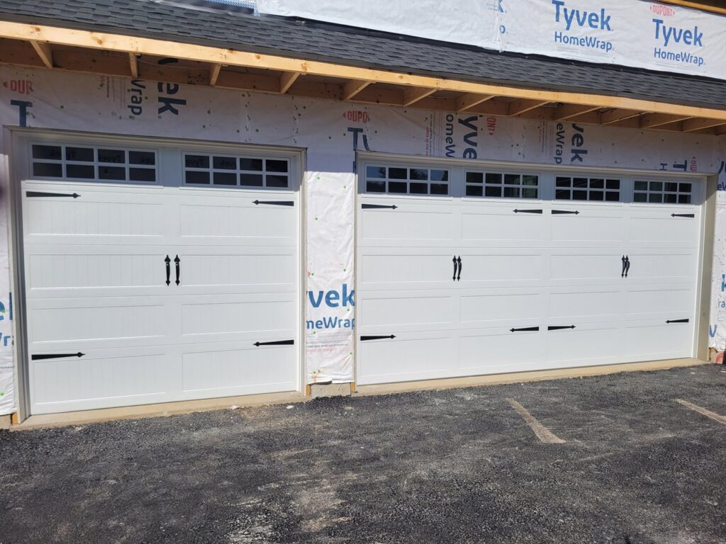 New white X-brace style garage doors installed on a home under construction by Access Door Systems in Uniontown, PA.
