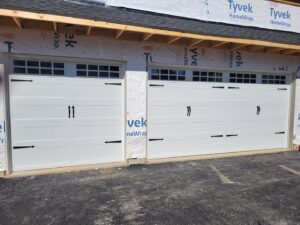 New white X-brace style garage doors installed on a home under construction by Access Door Systems in Uniontown, PA.