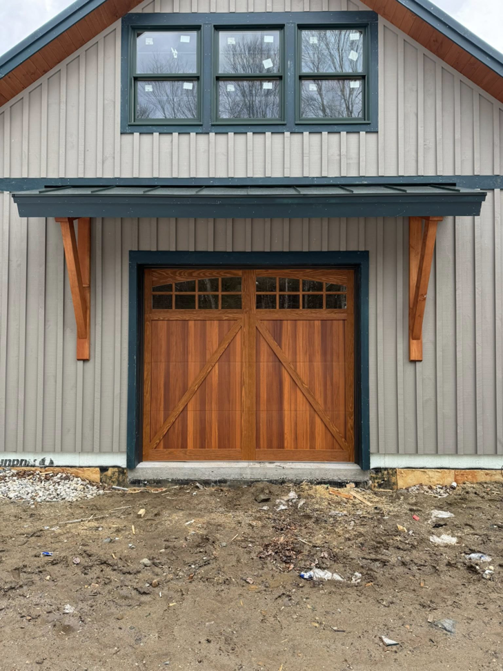A newly installed wooden garage door with windows on a building by Ski Door, Inc. in Center Rutland, VT.