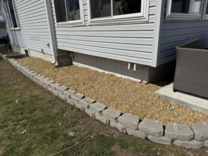 Newly installed rock bed with retaining wall blocks for landscaping by Elite Property Care in Albany, NY.