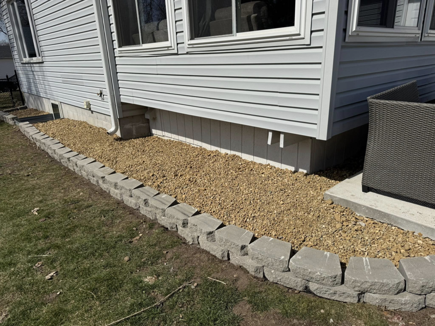 Newly installed rock bed with retaining wall blocks for landscaping by Elite Property Care in Albany, NY.