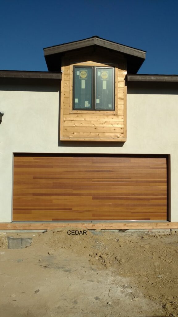 A newly installed modern wooden garage door on a house under construction by Garage Door Medics in Boise, ID.